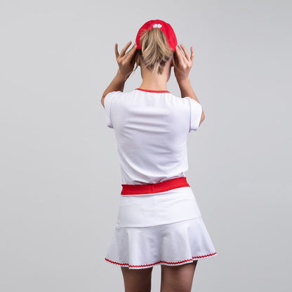 Person wearing a white outfit with red accents on a gray background