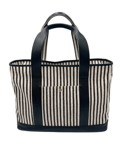 A striped tote bag with black leather handles and trim, featuring vertical black and cream stripes on a woven canvas body, shown against a plain white background.