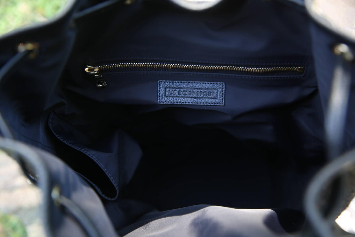 Close-up of the interior of a dark navy bucket bag, showing a zippered pocket with a blue brand label that reads 'UP DOWN SPORT'.