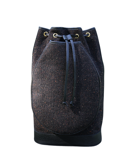 A dark blue and black speckled bucket bag with a drawstring closure and brass eyelets, shown against a plain white background.