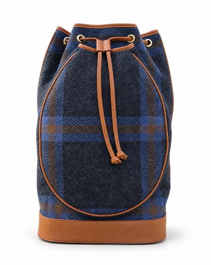 A navy blue and blue plaid wool bucket bag with tan leather trim, drawstring closure, and gold-tone metal eyelets, shown against a plain white background.
