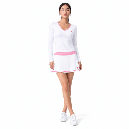 Woman wearing white tennis outfit with pink detailing and white sneakers on flat white background